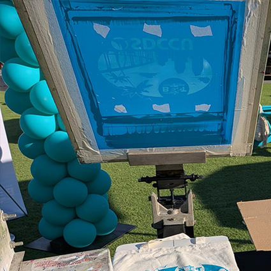 Screen with the SDCCU artwork loaded on the press at a live printing event